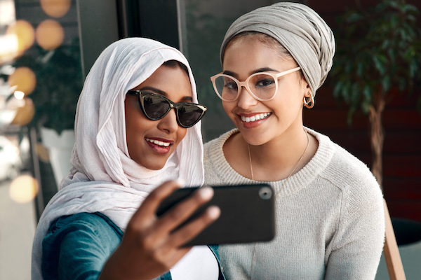 GettyImages-1182404489 Two woman posing for a photo with their smart phone
